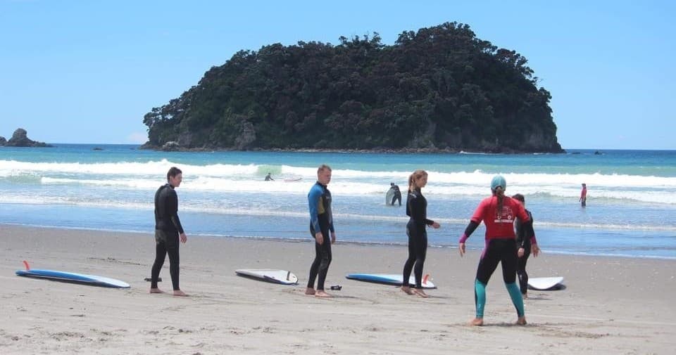 Surfers preparing on Mount Maunganui beach with island view