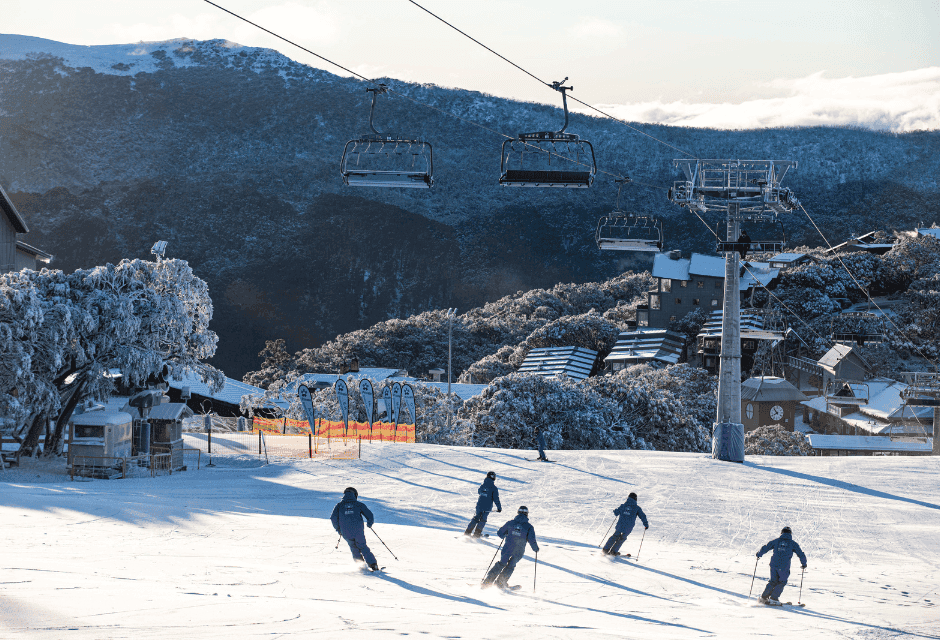 Skiers descending snowy slopes beneath chairlift at alpine resort