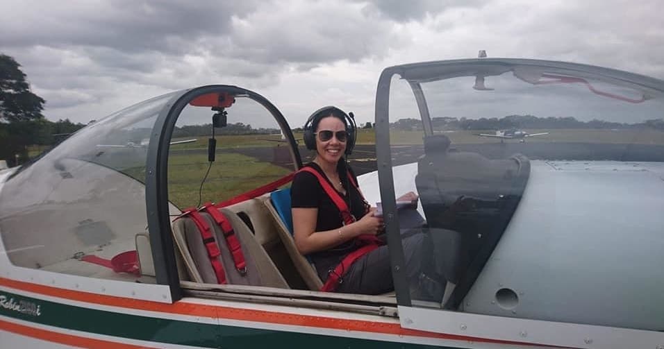 Pilot seated in cockpit of light aircraft on cloudy runway