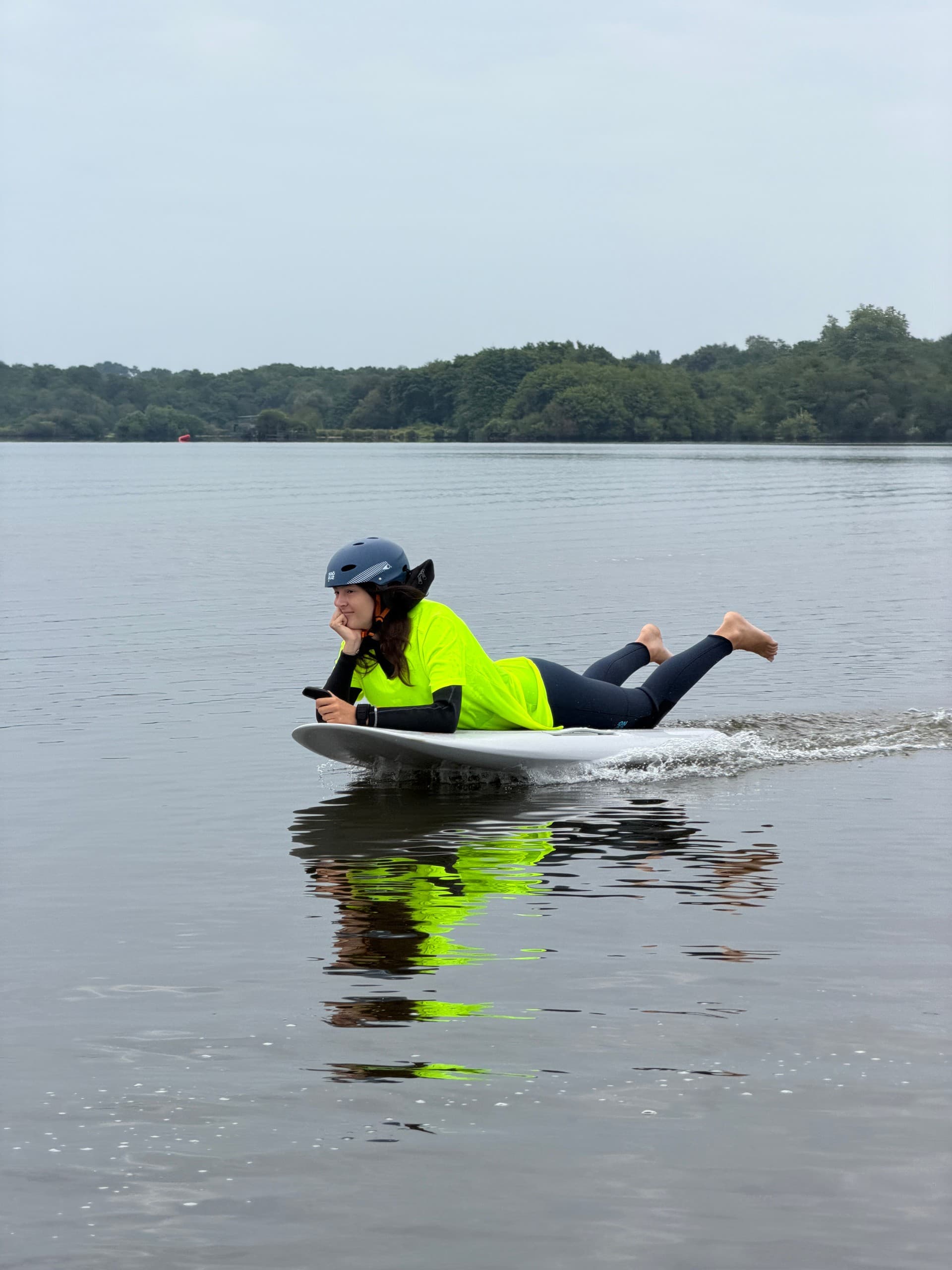 Person paddling e-foil in bright jacket on calm lake, foiling