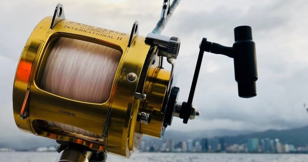 Gold fishing reel mounted on boat, deep-sea sportfishing scene