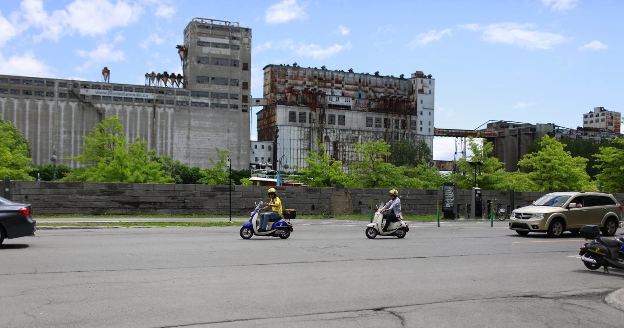 Group of scooter riders cruising urban industrial waterfront in Montreal