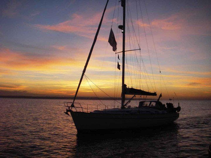 Sailing yacht silhouetted at colorful sunset over calm sea