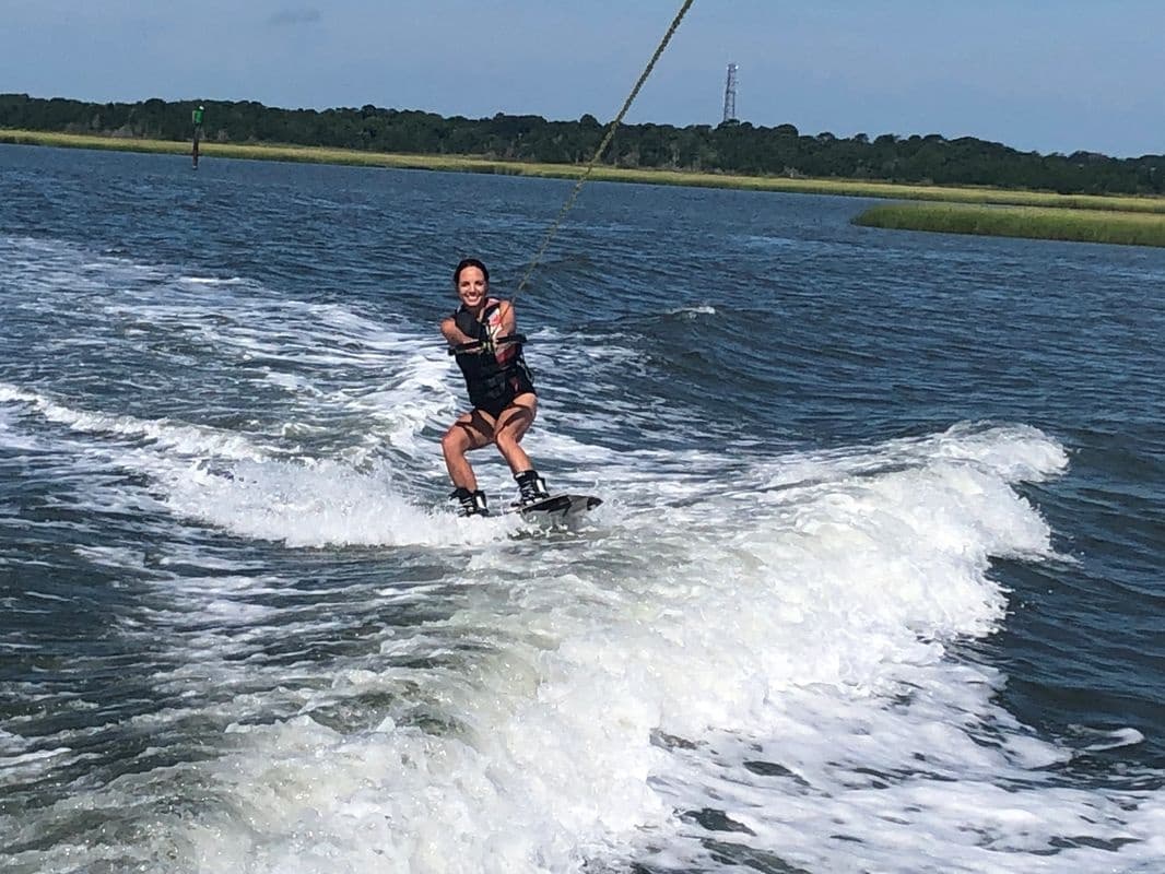 Wakeboarder carving wake on open bay during sunny day