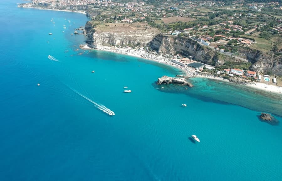 Aerial coastal panorama of turquoise bay with boats, Tropea Italy