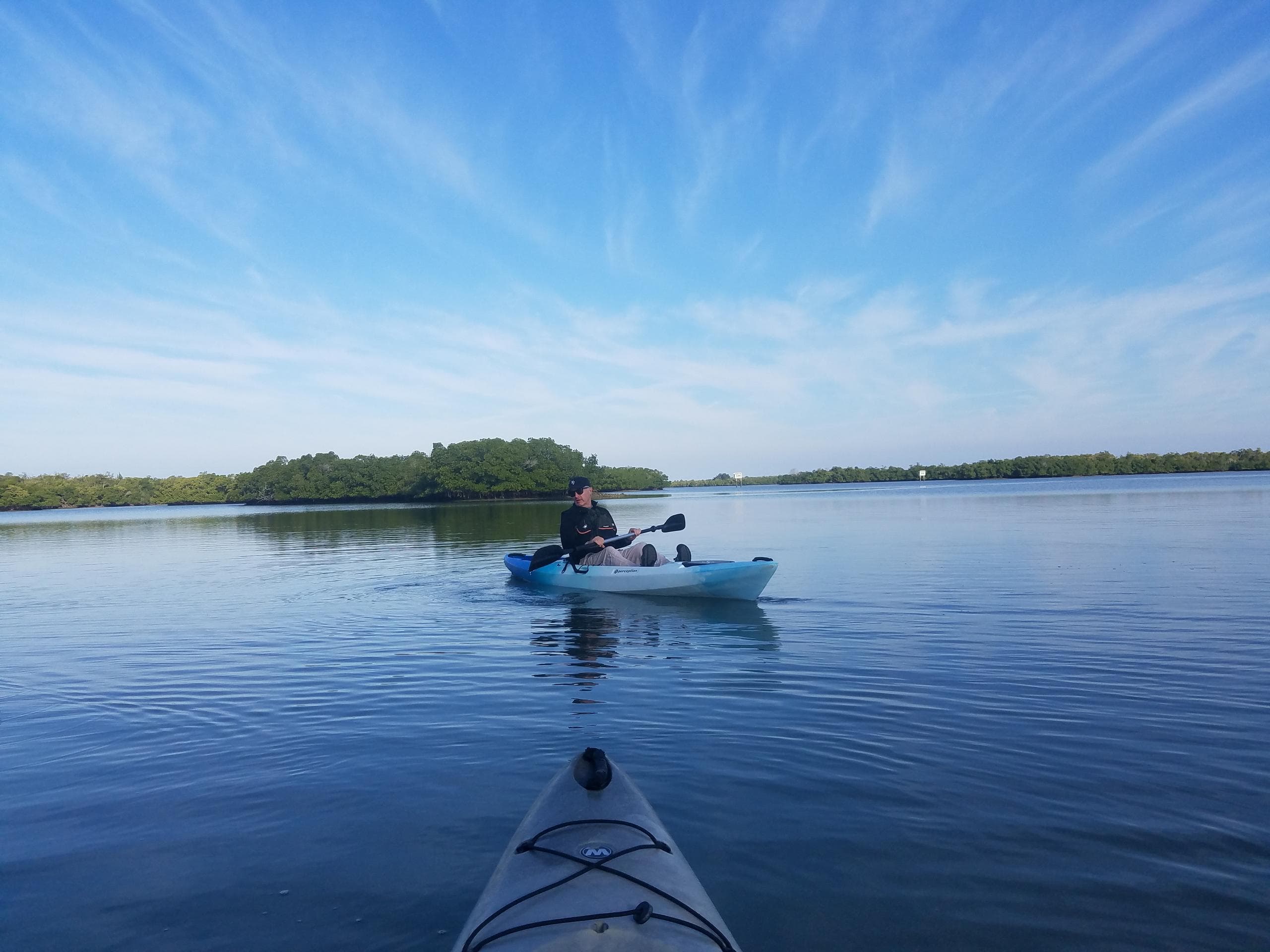 Kayaker's POV paddling across open coastal waters at sunrise