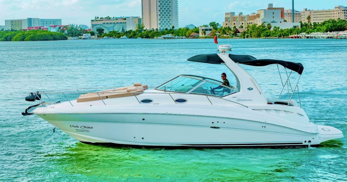 Luxury powerboat gliding across calm turquoise bay with skyline