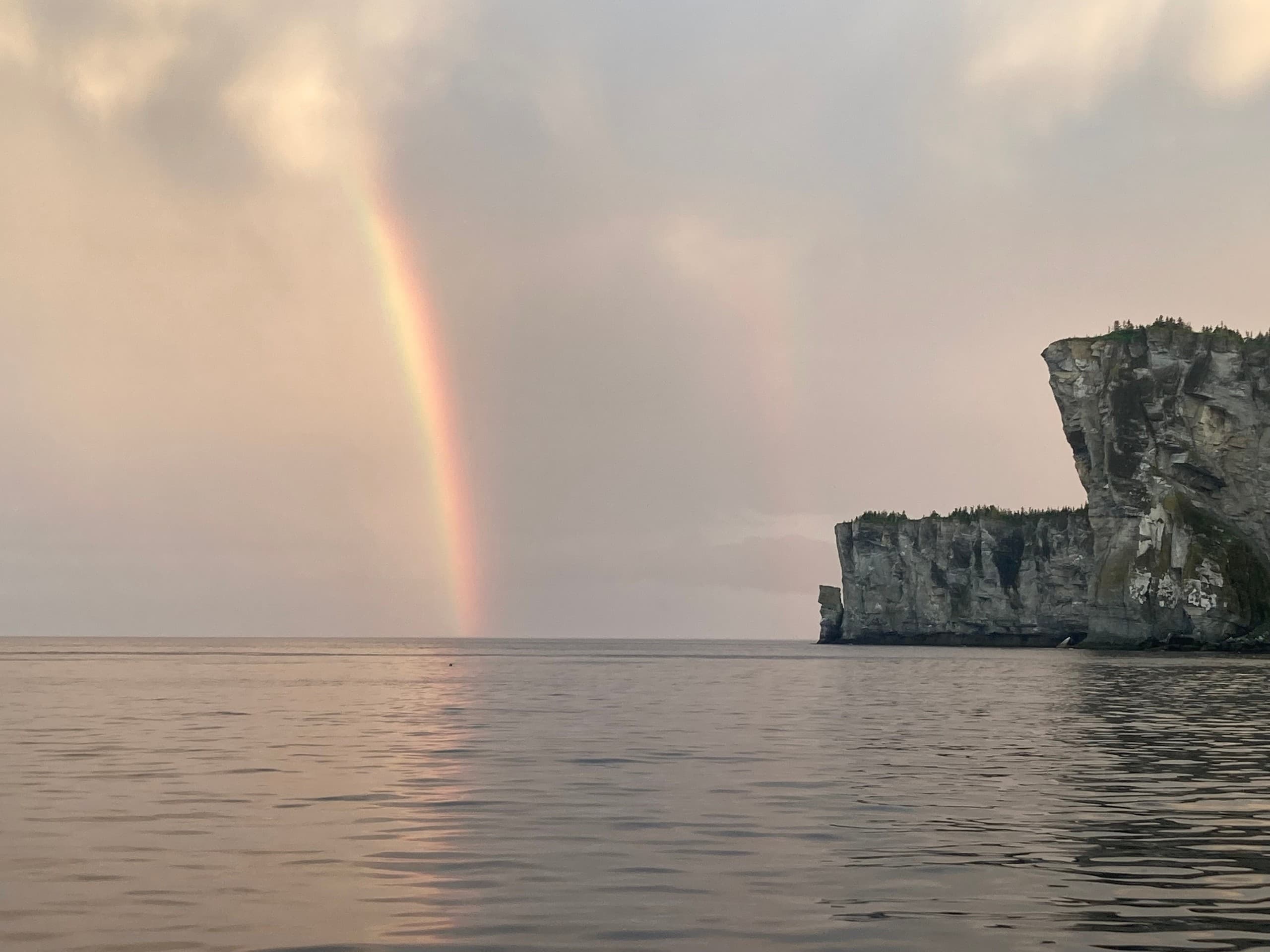 Rainbow over rugged cliff and open sea, Gaspé sunset vista