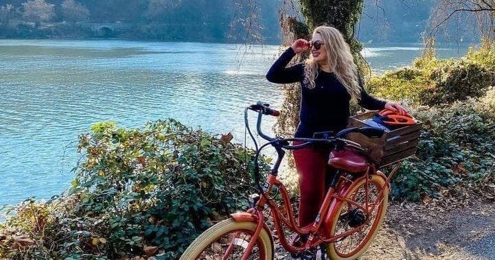 Woman pausing on lakeside cruiser bike ride enjoying waterfront view
