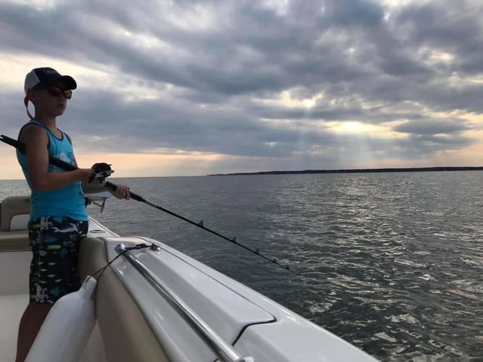 Youth rod fishing from boat at sunset on open coastal waters