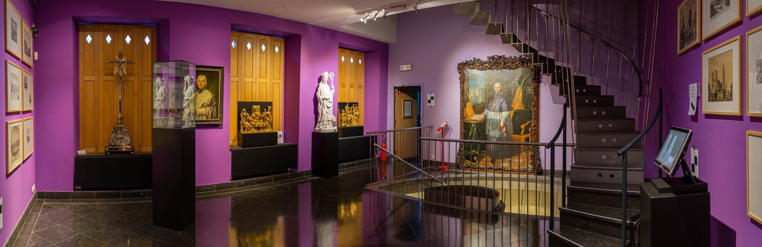 Indoor museum gallery with religious art and staircase in Liege