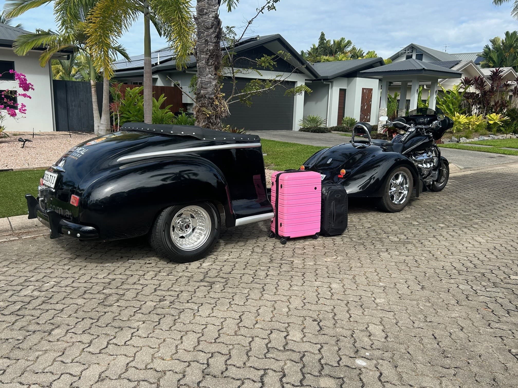Parked black trike and trailer with luggage in driveway