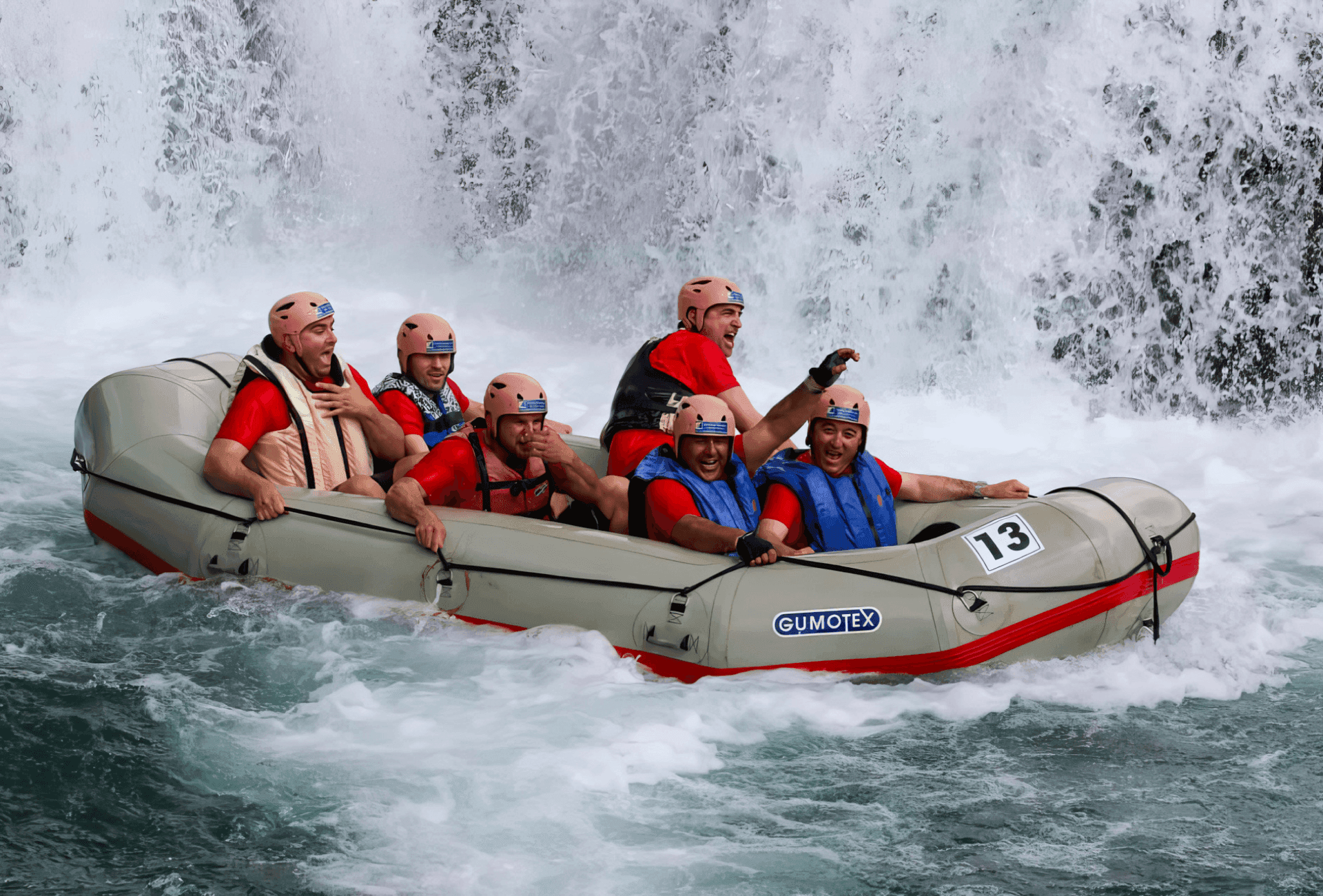 Whitewater rafters navigating turbulent rapids beneath a waterfall