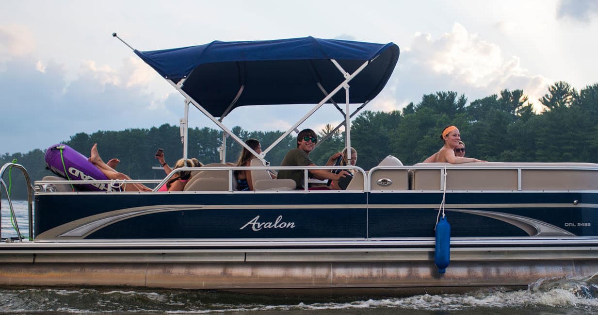Family enjoying pontoon boat cruise on scenic lake shoreline