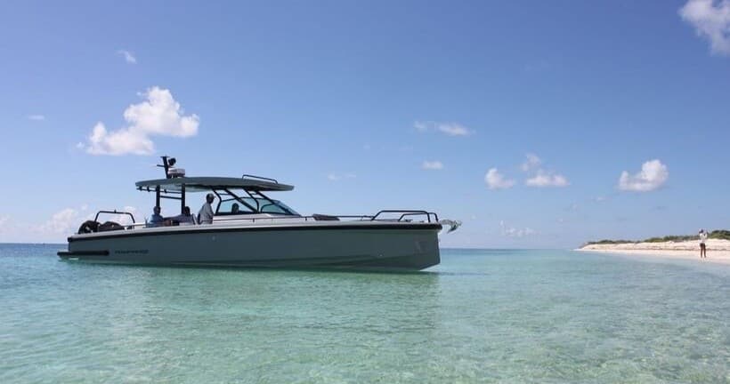 Sport boat anchored in crystal sea near sandy shoreline