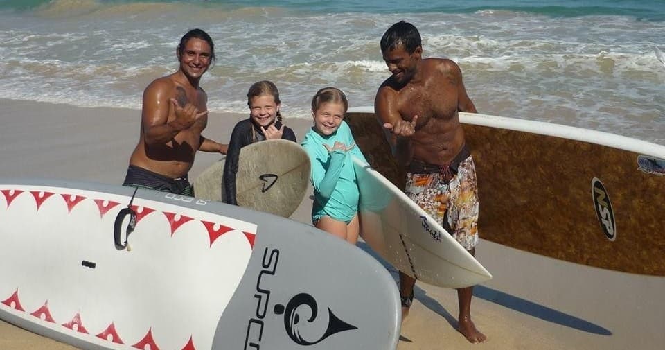 Family surf lesson on beach with instructors and multiple boards
