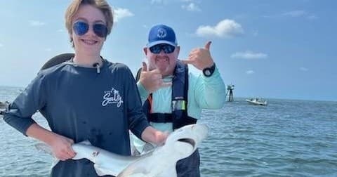 Father and teen holding caught shark in shallow North Myrtle Beach waters