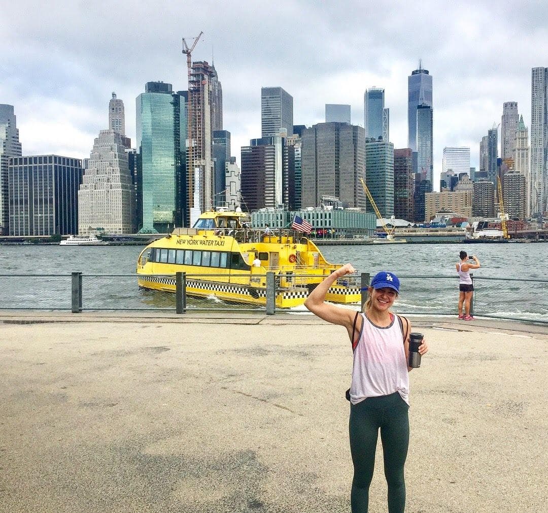 Runner posing by NYC waterfront with skyline and ferry
