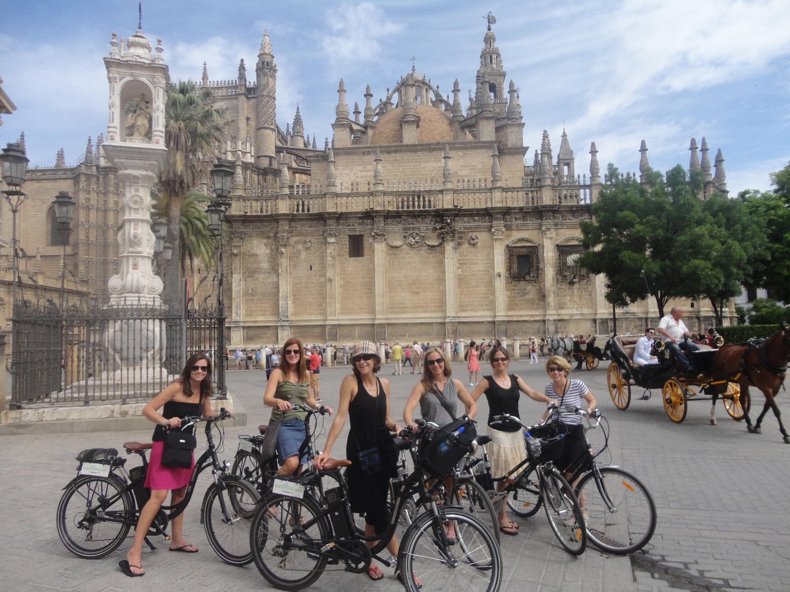Guided bike tour group posing by Seville cathedral exterior