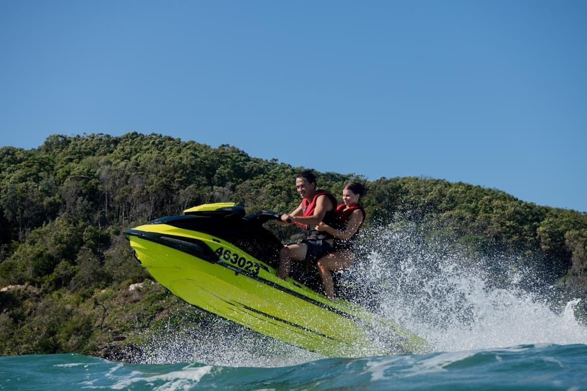 Bright green jetski jumping waves along coastal shoreline