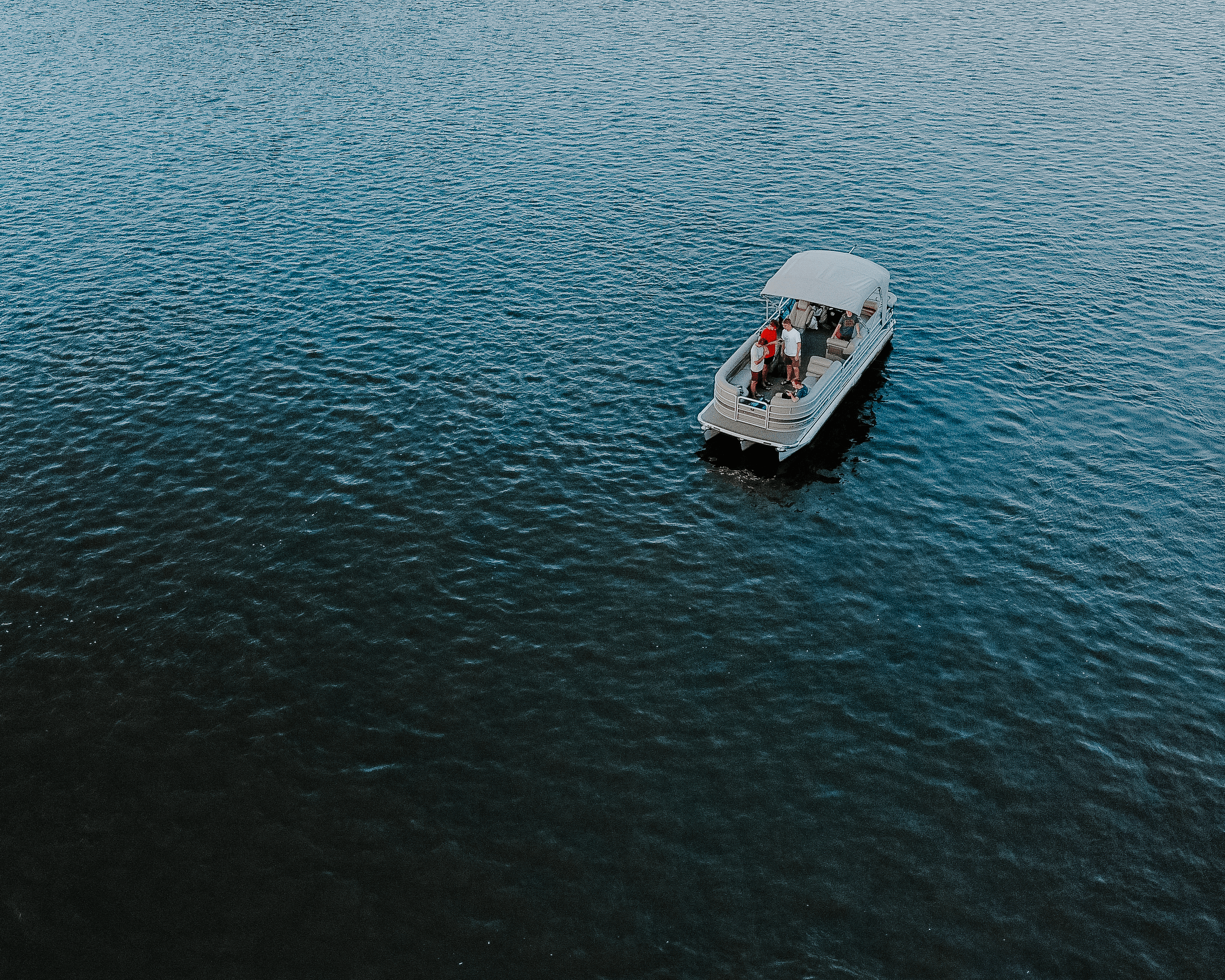 Aerial pontoon boat cruising expansive open coastal waters