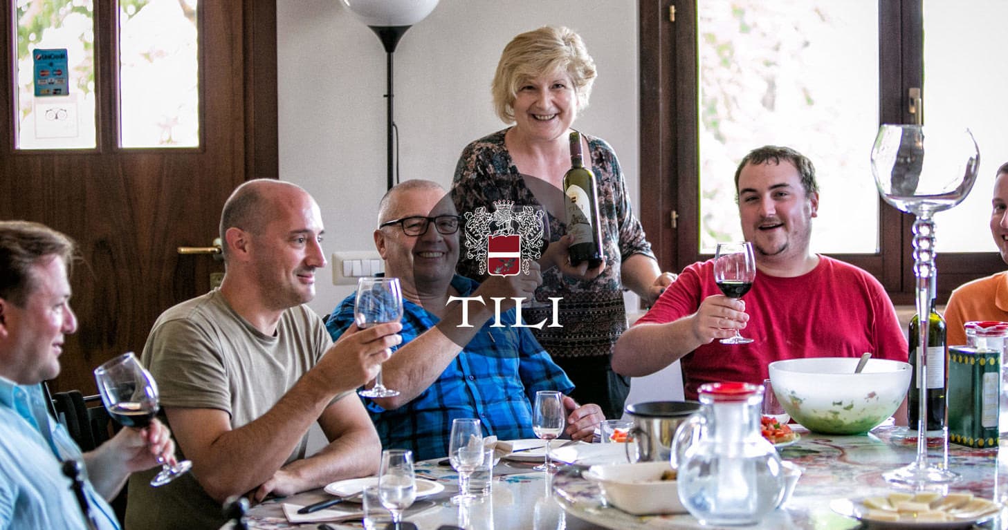 Group enjoying wine tasting and communal meal in rustic dining room