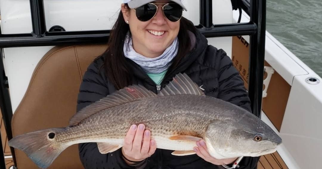 Angler holding redfish on sport boat in coastal inshore waters