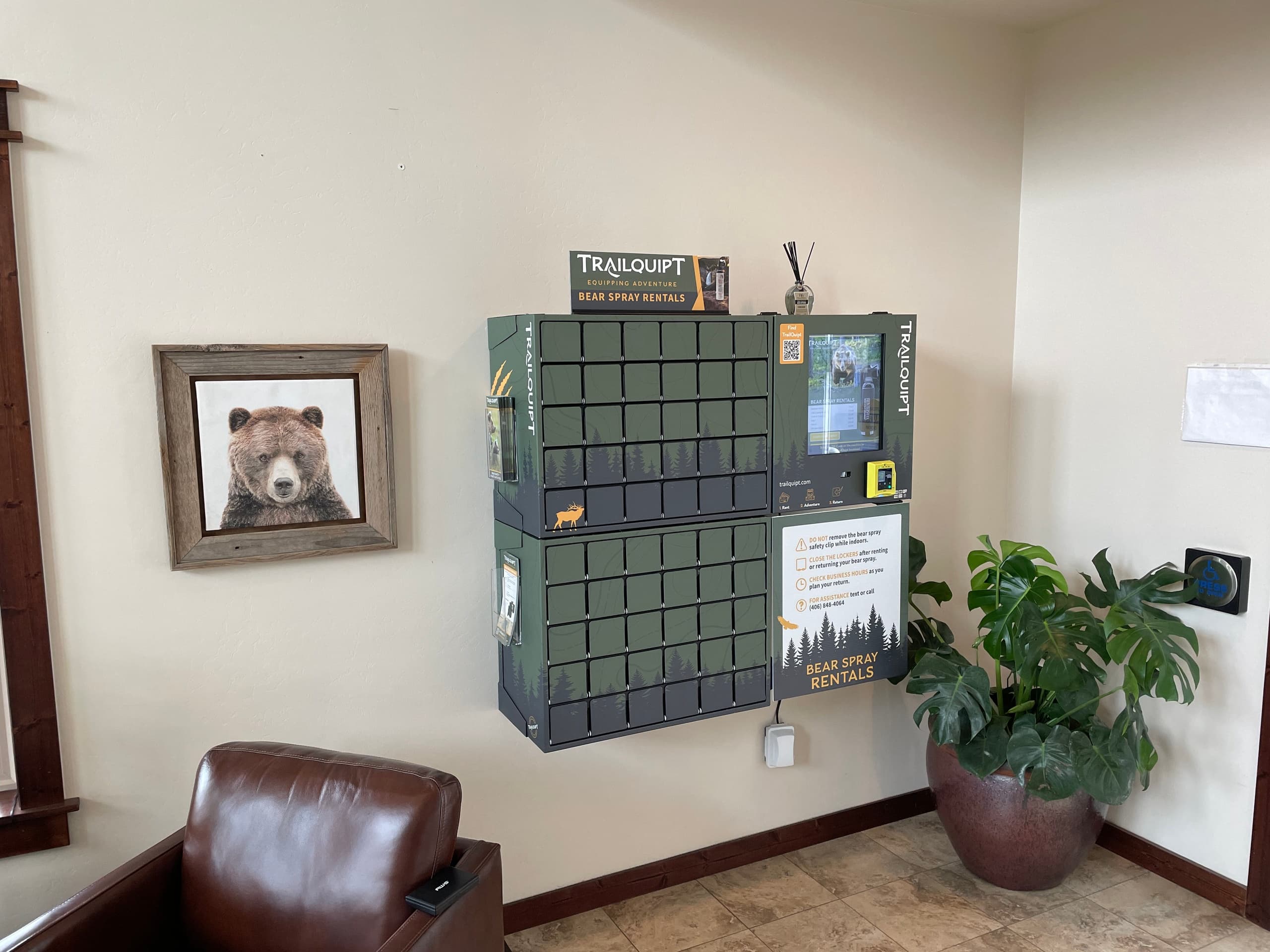 Indoor TrailQuipt bear spray vending locker in lobby by chair