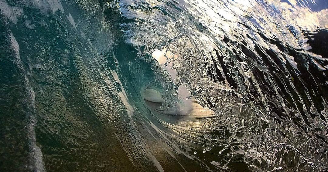Surfer riding a barreling ocean wave off tropical shore