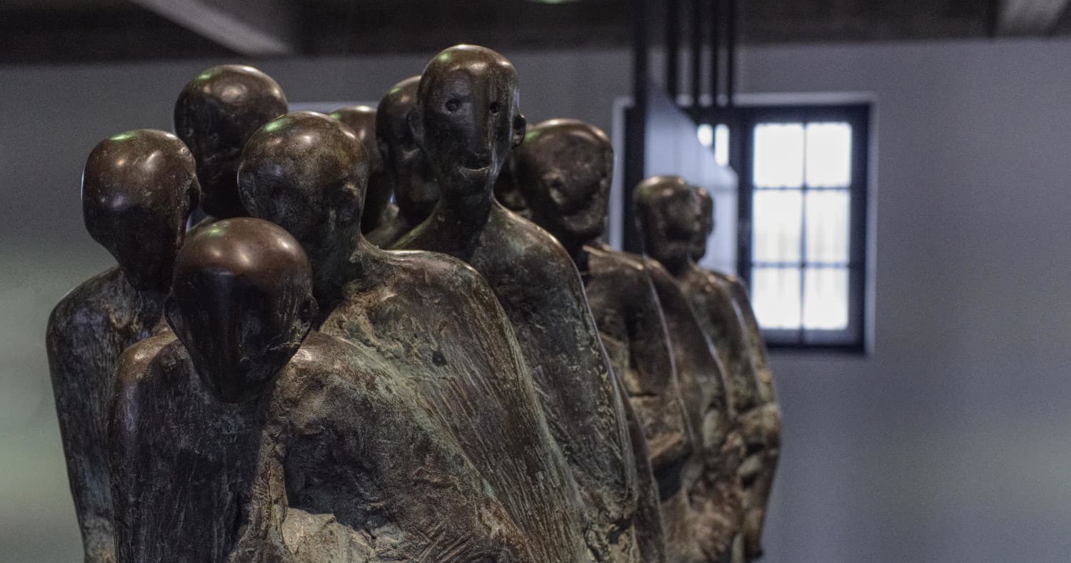 Bronze group sculpture inside Dachau memorial museum, somber figures