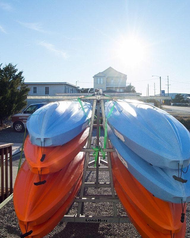 Stacked kayaks and paddleboards on sunny seaside rack