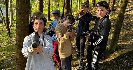 Young group playing forest laser-tag style game in woodland