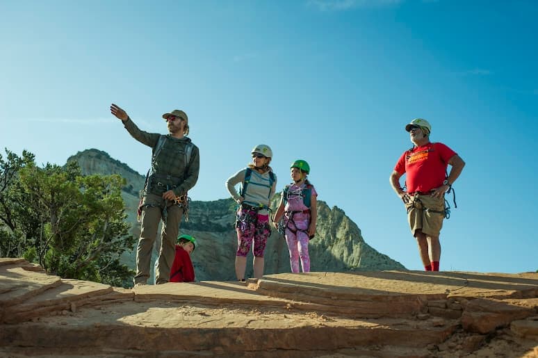 Family hikers pausing on sandstone overlook under blue sky