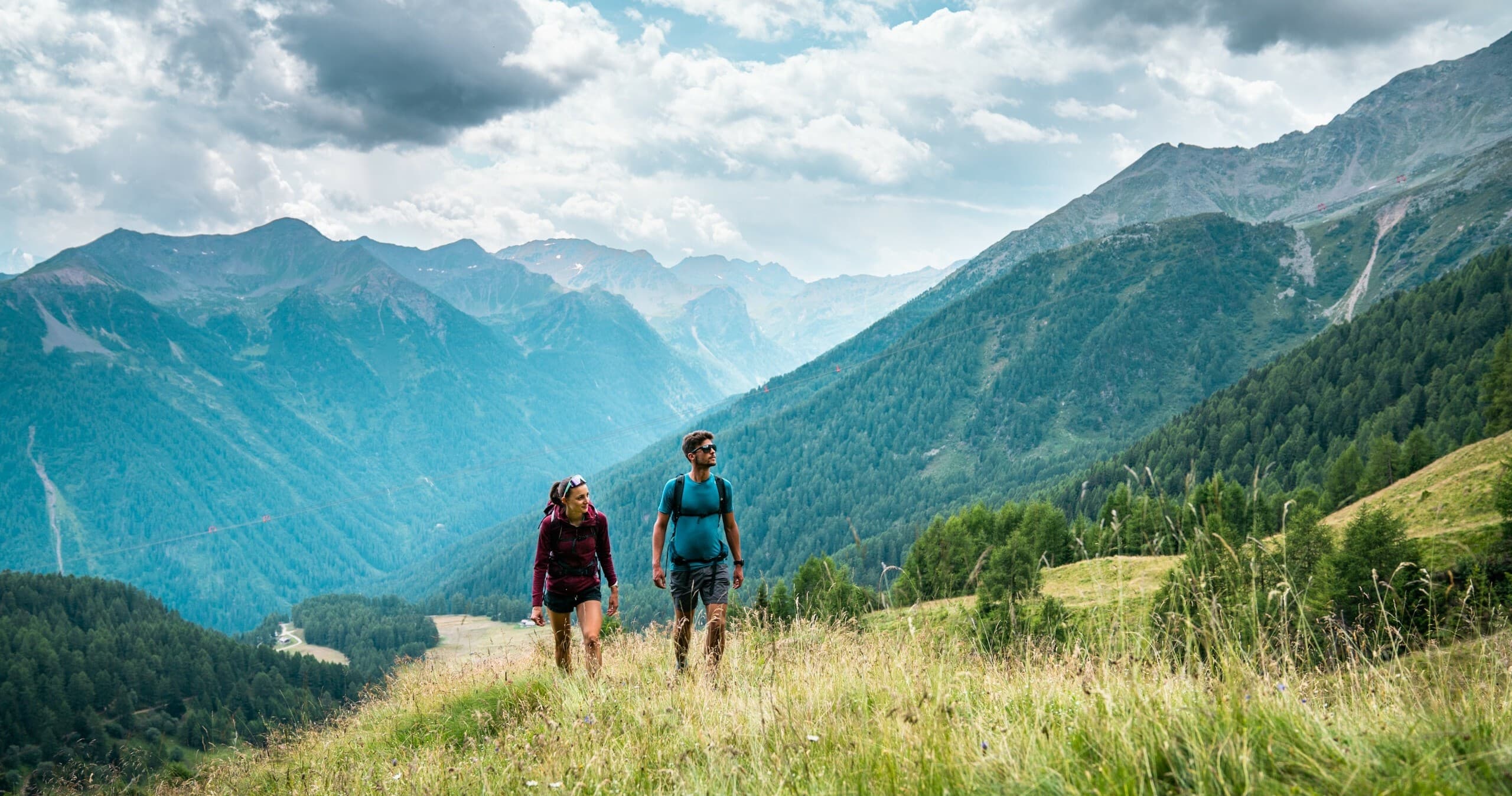 Two hikers walking toward panoramic alpine mountain vista