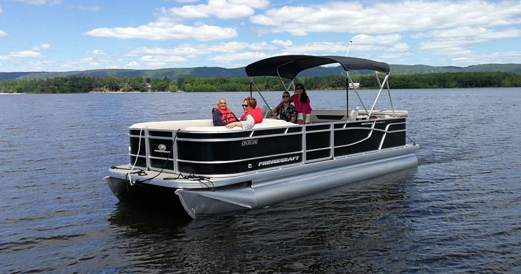 Pontoon cruising on lake with family under blue sky, leisure trip