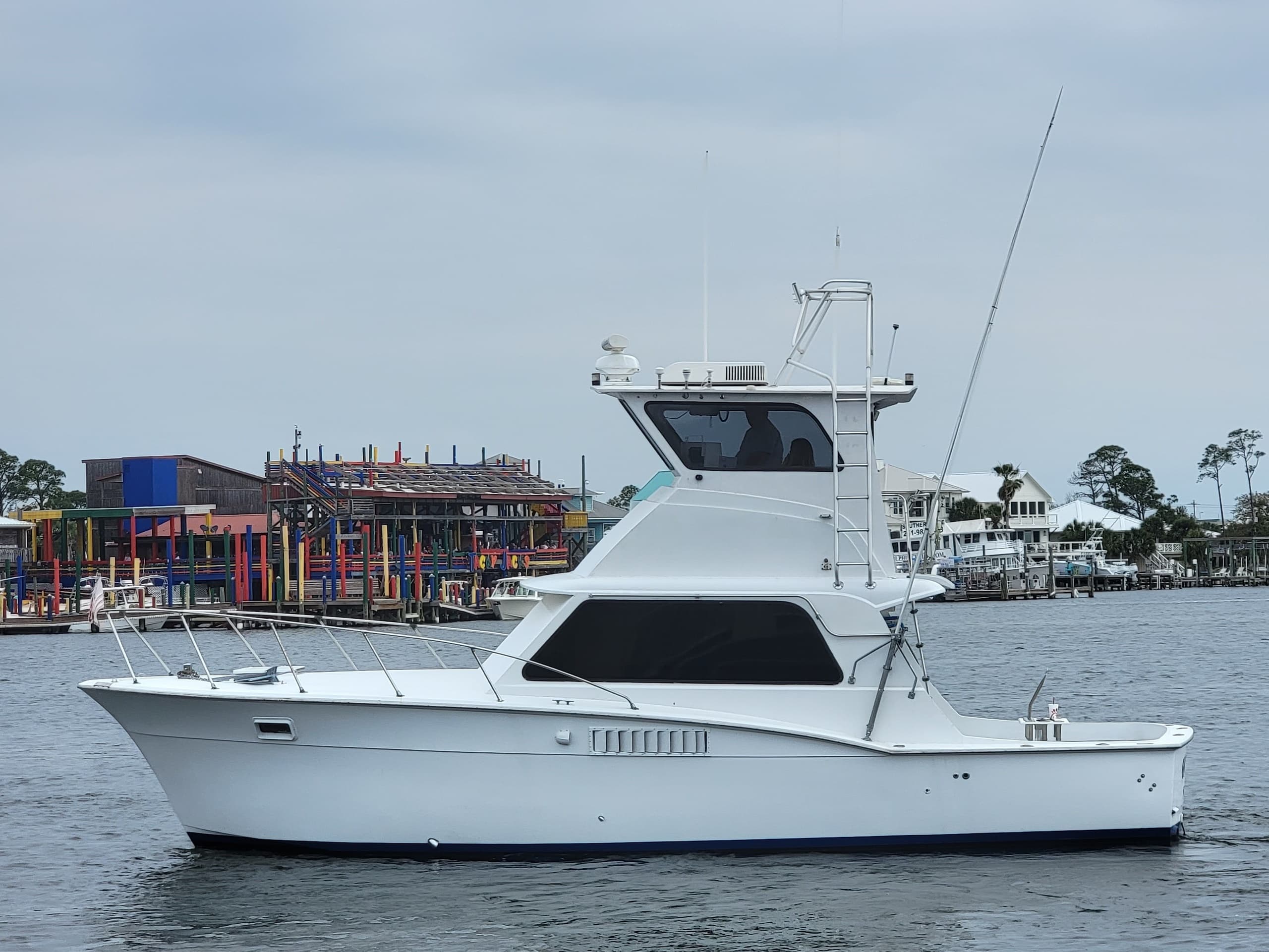 White sportfishing yacht cruising coastal harbor, charter trip