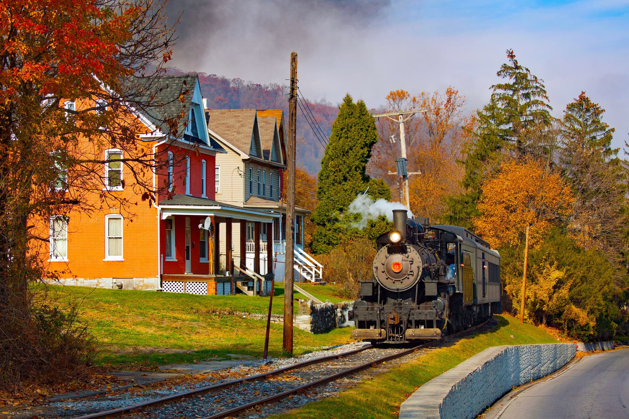 Steam train passing autumn countryside near historic station ride