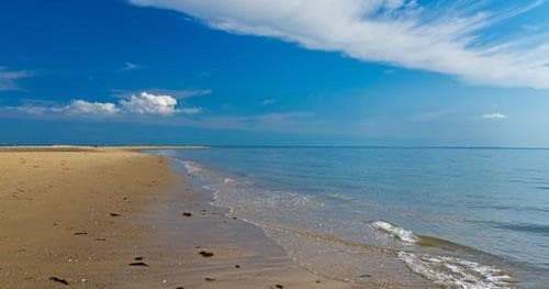 Wide sandy Cape Cod beach with calm ocean and blue sky