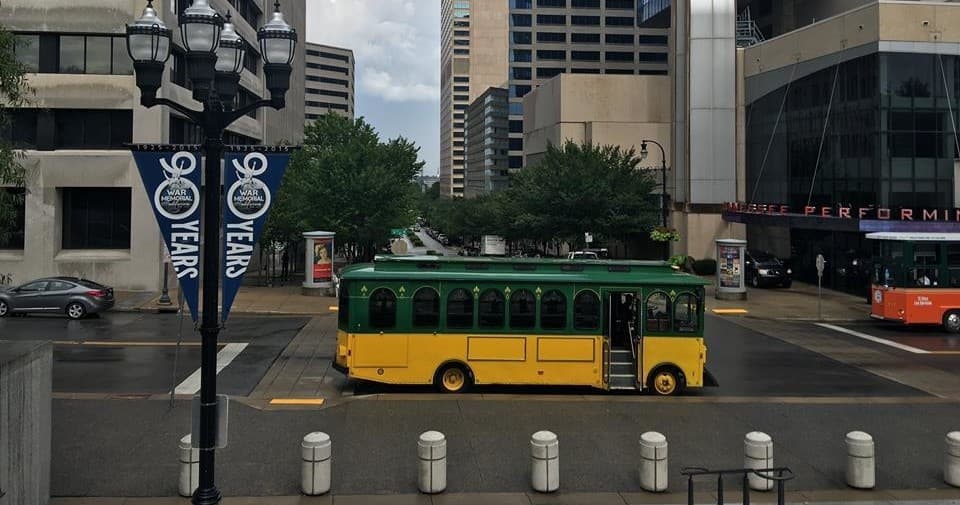 Green-yellow city trolley rolling down downtown street sightseeing tour