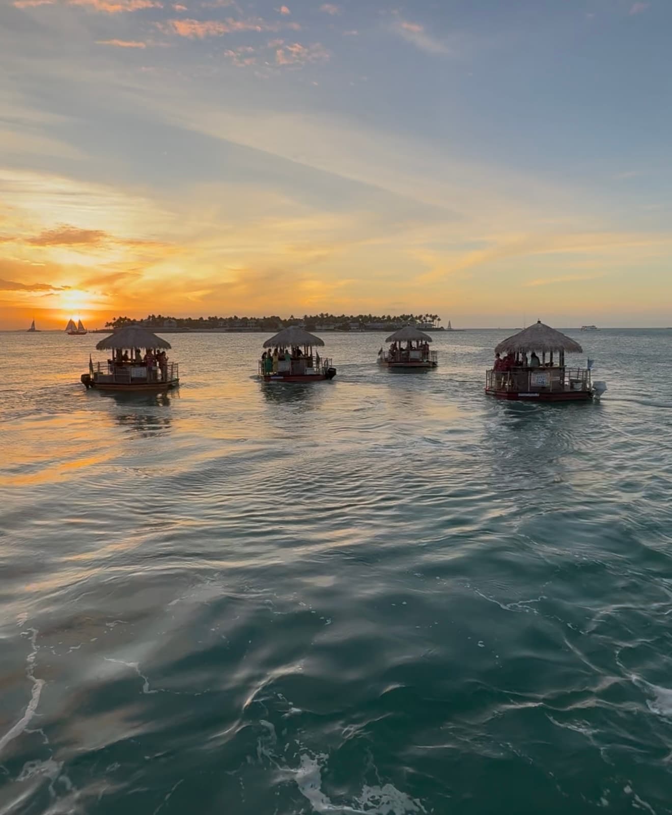 Sunset tiki boats cruising calm Key West waters at dusk