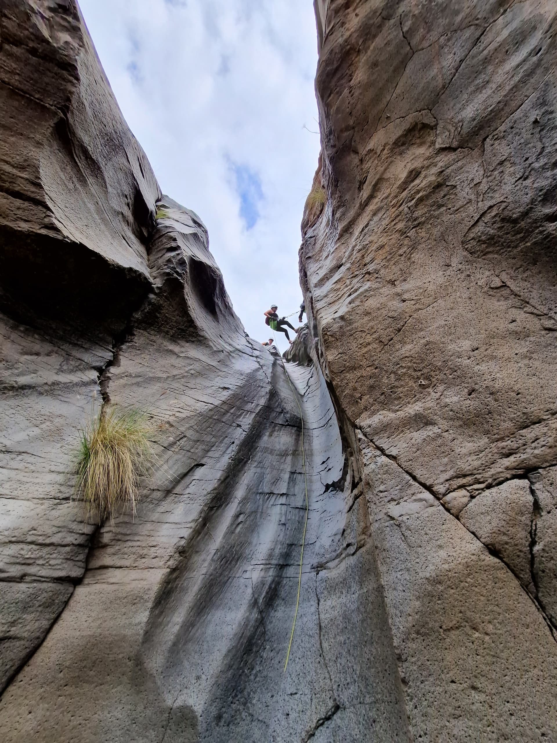 Canyon rappelling through narrow slot canyon toward sky