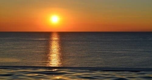Sunset over calm ocean horizon for coastal kayaking trips