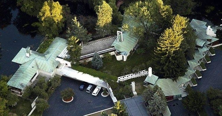 Aerial view of forested riverside house complex with dock