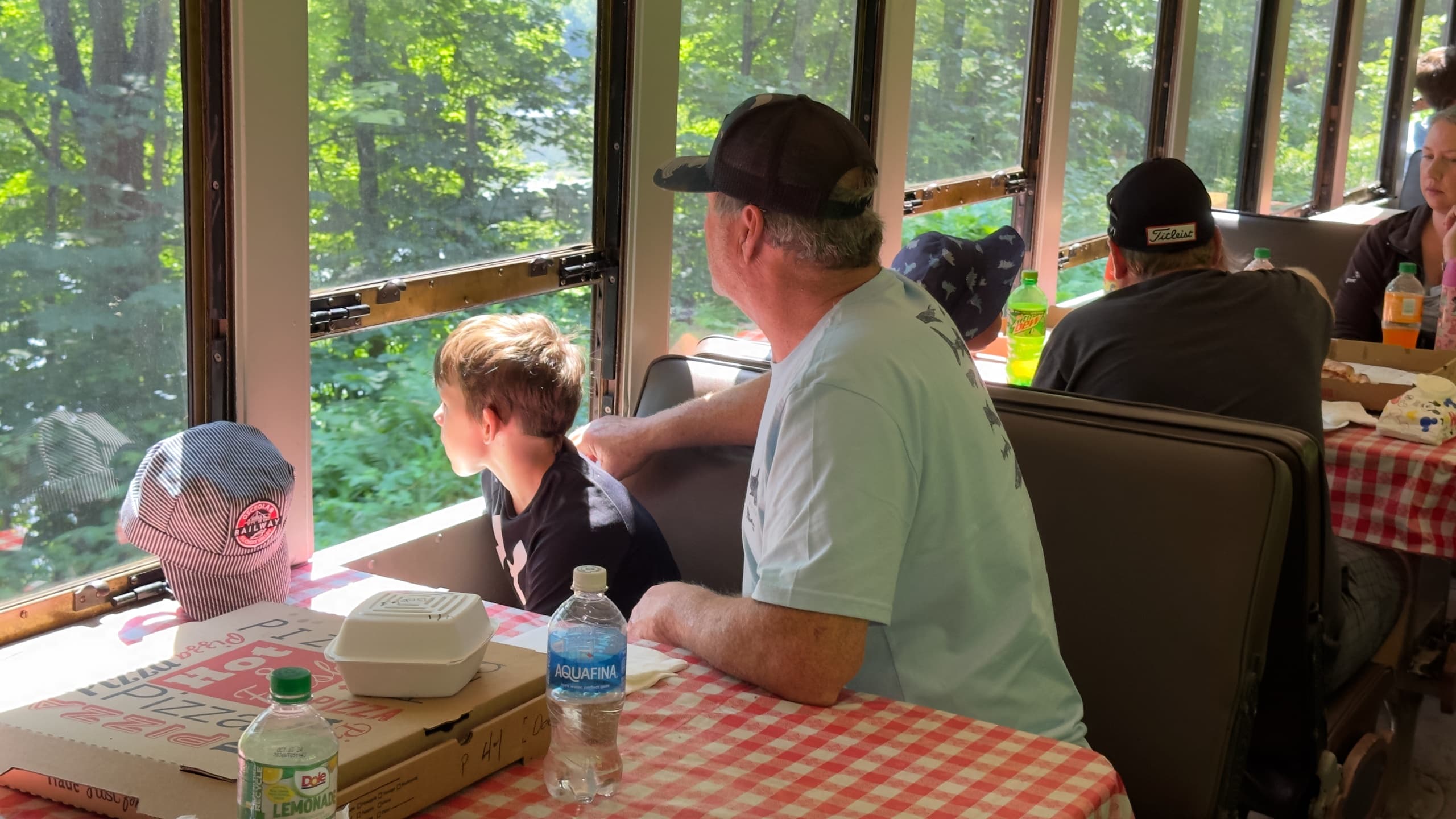 Passengers dining on scenic train looking out wooded valley windows