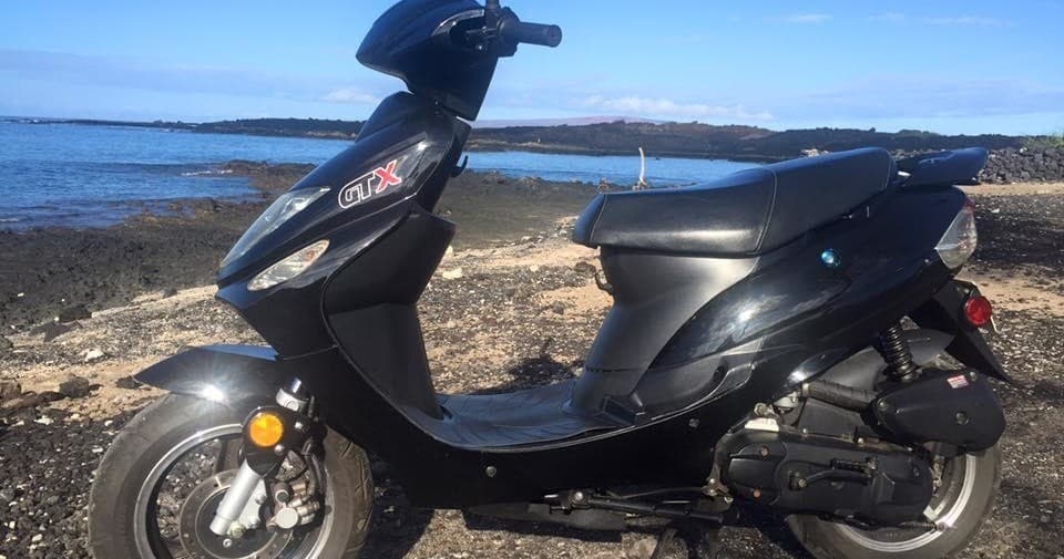 Scooter parked on rocky Hawaiian shoreline with ocean view