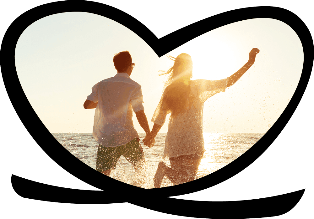 Couple running hand-in-hand through surf at sunset beach