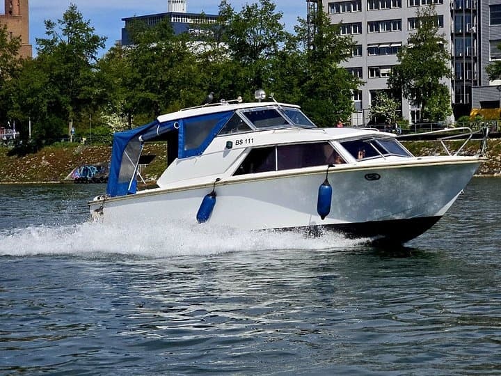 White cabin boat speeding on Basel's river, waterfront views