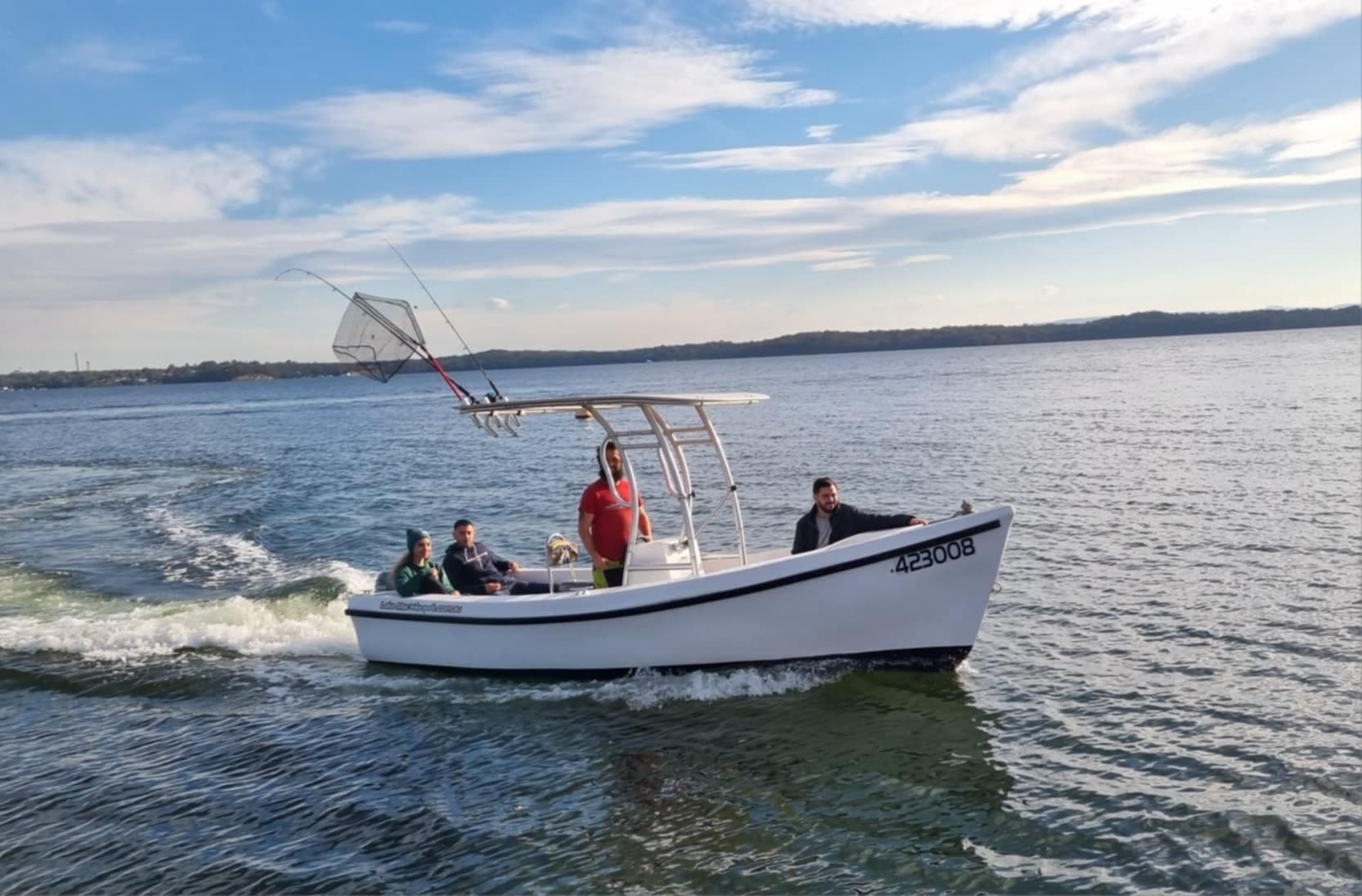 Motorboat cruising across open lake creating wake, passengers aboard