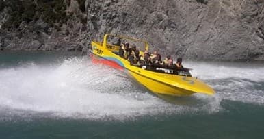 Yellow jet boat carving rapids through narrow mountain gorge