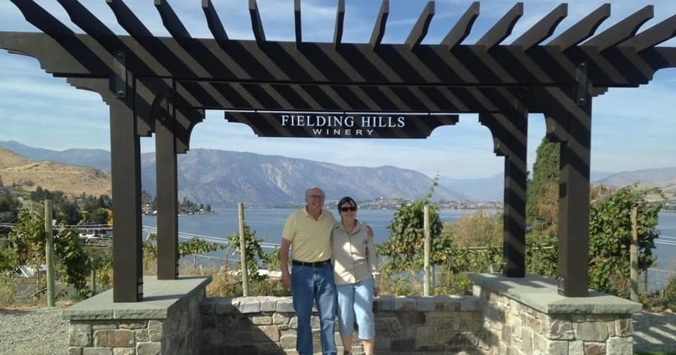 Couple posing under vineyard pergola with panoramic lake overlook